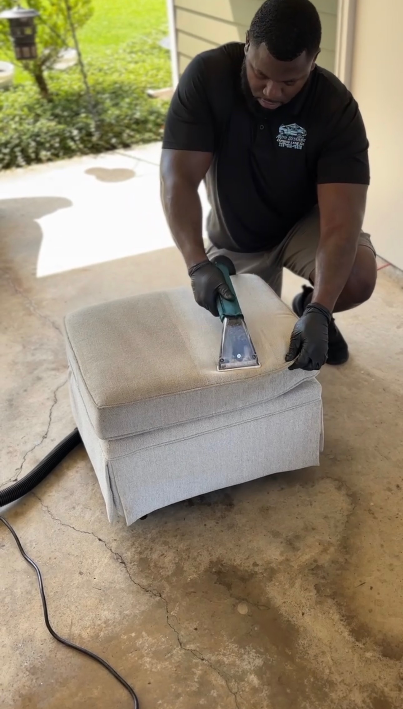 Technician extracting dirt from a light gray upholstered ottoman in Baton Rouge, LA